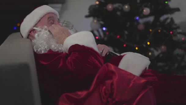 Vista lateral retrato de homem caucasiano maduro em traje de Papai Noel dormindo no fundo da árvore de Natal. Cansado Santa masculino descansando após dia de trabalho difícil . — Vídeo de Stock