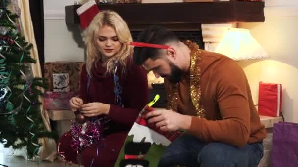 Närbild av unga kaukasiska man och kvinna väljer dekorationer för julgran hemma. Make och fru dekorera hus på nyårsafton tillsammans. Lycka, nöje, semester. — Stockvideo