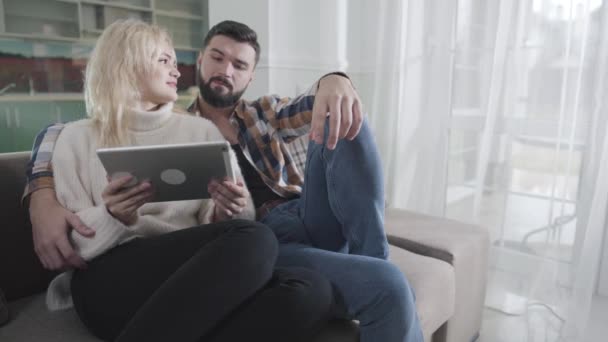 Retrato de la joven familia caucásica eligiendo la compra con el uso de la tableta digital. Hombre guapo y mujer hermosa haciendo compras en línea en casa. Comercio electrónico, tecnologías, inalámbrico, Internet . — Vídeos de Stock