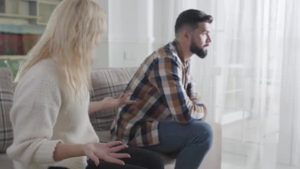 Homme barbu irrité en arrière-plan écoutant sa femme ennuyeuse ou sa petite amie lui crier dessus. Femme blanche blonde se disputant avec son mari à la maison. Problèmes de mariage, malentendu . — Video