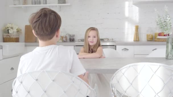 Retrato de menina branca bonito sentado à mesa como menino morena dando sua caixa de presente. Pequena senhora recebendo presente para o aniversário ou na véspera de Natal. Feriados, felicidade, prazer . — Vídeo de Stock