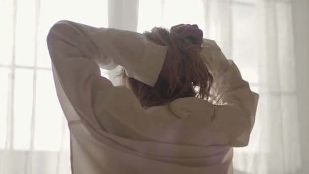 Close-up achteraanzicht van blonde blanke meisje stretching en aanraken van haar in zonnestralen. Jonge vrouw wakker in de ochtend thuis. — Stockvideo