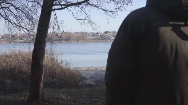 Vista posteriore dell'uomo adulto caucasico con coda di cavallo che cammina verso il lago autunnale. Turista attivo che si gode una giornata di sole all'aperto. Tempo libero, felicità, stile di vita . — Video Stock