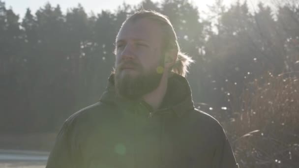 Portrait of handsome adult Caucasian man standing in sunlight in autumn forest. Male tourist enjoying his vacation outdoors. Lifestyle, travelling, tourism. — 비디오