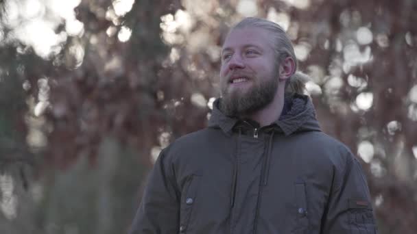 Portrait of smiling adult Caucasian man at the background of autumn forest. Happy male tourist enjoying his travel outdoors. Leisure, lifestyle, happiness. — 비디오