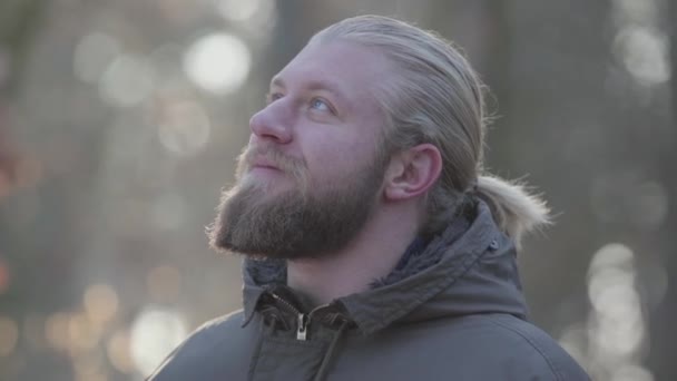 Detailní záběr pohledného bělocha s šedýma očima, jak dýchá čerstvý vzduch. Muž turista si užívá své cesty v podzimním lese. Štěstí, volný čas, životní styl. — Stock video