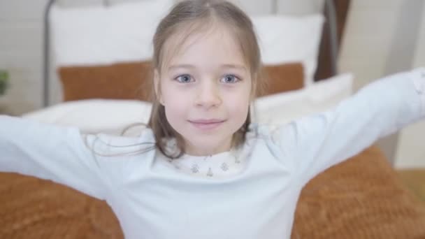 Vista superior de un lindo niño caucásico disfrutando de los fines de semana en casa. Niña alegre cayendo de nuevo en la cama y riendo, cámara moviéndose alrededor de la cara de los niños. Alegría, infancia, ocio . — Vídeos de Stock