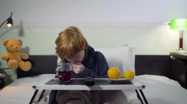 Öksüren beyaz bir çocuğun portresi uzaktan kumandayı ele alıyor ve televizyon kanallarını değiştiriyor. Yatakta çay ve portakalla tepsinin önünde oturan kızıl saçlı tatlı çocuk. Hastalık, sağlık, yaşam tarzı.