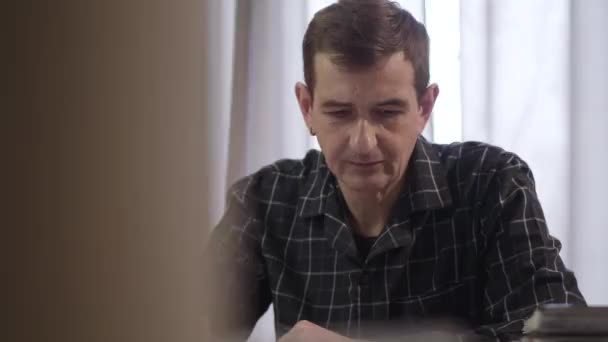 Κοντινό πλάνο πορτρέτο του συμπυκνωμένου Καυκάσιου ενήλικα άνδρα που γράφει στο σπίτι ως δαχτυλίδια smartphone. Χαρούμενος μεσήλικας με σκουλαρίκι που μιλάει στο τηλέφωνο μέσα. Τρόπος ζωής, σύγχρονες τεχνολογίες, επικοινωνία. — Αρχείο Βίντεο