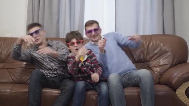 Retrato de alegre hijo, padre y abuelo caucásico cogiendo algo invisible con la mano y moviéndose. Familia viendo películas en gafas 3D. Diversión, alegría, ocio . — Vídeos de Stock