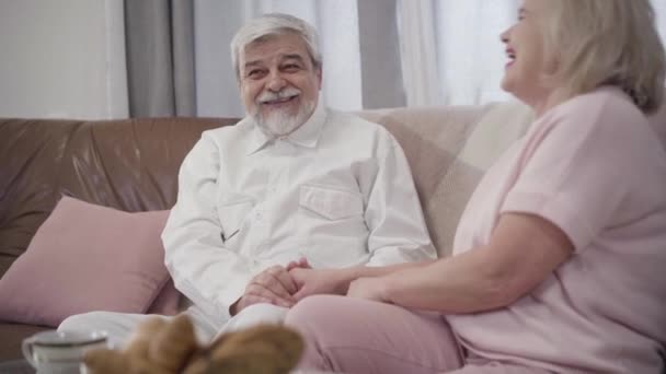Retrato de hombre mayor caucásico alegre y mujer madura hablando y riendo en casa. Feliz pareja alegre de jubilados pasando la noche juntos en el interior. Amor, matrimonio, felicidad, alegría . — Vídeo de stock