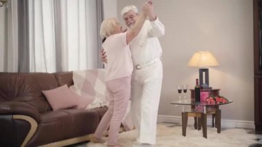 Mutlu, olgun beyaz çiftin kapalı mekanda romantik dansı. Neşeli koca güzel karısını döndürüyor ve gülümsüyor. Tatil, Sevgililer Günü, birlik, sonsuz aşk.