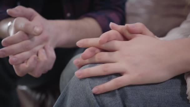 Extreme close-up van vrouwelijke blanke handen die jeans en elkaar masseren. Onherkenbare man op de achtergrond die handpalmen bij elkaar houdt. Bezorgde mensen die op nieuws wachten. Ondersteuning, eenheid, levensstijl. — Stockvideo