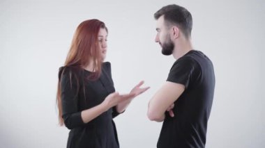 Siyah elbiseli, beyaz arka planda tartışan genç, asabi beyaz bir çift. Yakışıklı sakallı adam ve kavga eden güzel kızıl saçlı kadın. Evlilik sorunları, ilişki sorunları, çatışma.