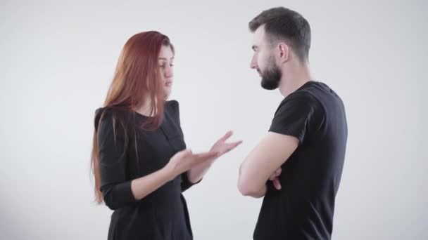 Young irritated Caucasian couple in black clothes arguing at white background. Handsome bearded man and beautiful redhead woman quarreling. Marriage difficulties, relationship problems, conflict. — Stock Video