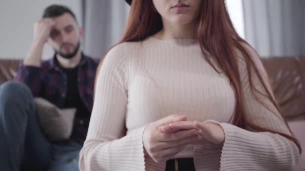 Méconnaissable jeune femme caucasienne enlever l'alliance comme homme barbu flou assis à l'arrière-plan. rupture, divorce, problèmes relationnels . — Video
