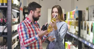 Şarap pazarında içki içmeyi seçen genç beyaz erkek ve kadın. Lüks şarap dükkanından içki alan güzel bir çift. Alkol, yaşam tarzı, şarap garsonu..