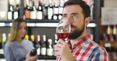 Sakallı, camdan kırmızı şarap içen yakışıklı, kendine güvenen beyaz adamın yakın çekimi. İçki dükkanında, meslekte, meslekte, yaşam tarzında alkol tüketimini azaltan profesyonel şarap garsonu..