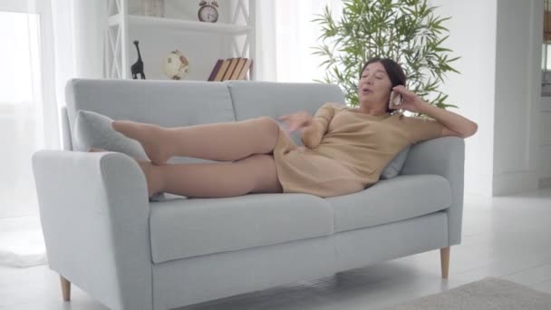 Elegant Caucasian senior woman standing up from couch with smartphone and leaving. Middle-aged stylish lady chatting at home on retirement. Active rich female retiree enjoying free life. Lifestyle. — Stock Video