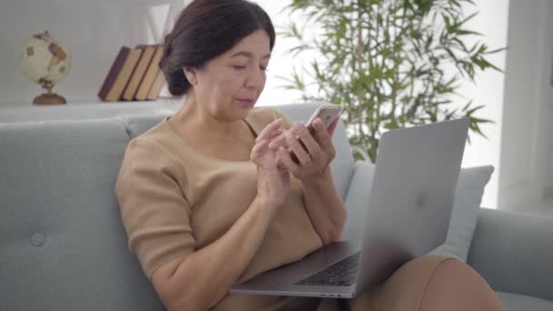 Lento de mujer caucásica madura tocando la pantalla del teléfono inteligente y sonriendo. Mujer de negocios senior positiva navegando por Internet en interiores. Negocios, éxito, estilo de vida. Movimiento lento . — Vídeos de Stock