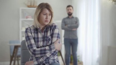 Arka planda bulanık bir adam olarak oturan üzgün, beyaz kadın portresi. Üzgün bir eş ve sakallı bir koca ilişki sorunları yaşıyor. Evlilik, yaşam tarzı, sorun..