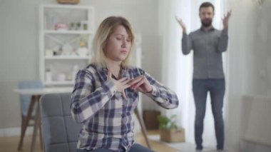 Gergin, beyaz bir kadının portresi evlilik yüzüğünü çıkarıp arka planda kocasına uzatıyor. Gergin genç adam, karısı ayrılırken duygusal olarak el kol hareketi yapıyor..