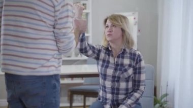 Saldırgan bir adama yumruk atan, yaralı gözlü, sarışın, beyaz bir kadın. Koca, karısının elini itiyor. Eşler içeride kavga ediyorlar. Aile içi şiddet ve istismar, evlilik sorunları.