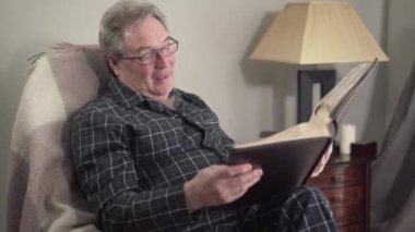 Son sınıf Kafkasyalı emeklinin fotoğraf albümü izleyip gülümseyen portresi. Yaşlı adam akşamları evdeki anılarını hatırlıyor. Yaşam tarzı, hatırlama, boş zaman, nostalji..