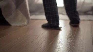 Kamera, pijamalı ve terlikli neşeli emeklinin evdeki pencereye doğru dans edişini takip ediyor. Mutlu, yaşlı bir adam emeklilikte evde eğleniyor. Yaşam tarzı, neşe, rahatlık.