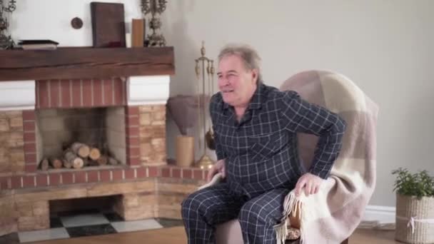 긍정적 인 성숙 한 백인 남자 의자에서 일어나 앉아 등에 갑자기 심한 통증때문에. 노인들의 건강 문제, 노화 개념, 의학적 인 문제들. — 비디오