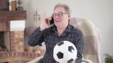 Telefonda konuşan ve elinde futbol topu tutan yaşlı, pozitif bir adamın portresi. Gözlüklü, spora meraklı neşeli, Kafkasyalı emekli. Formda kalmak, aktif yaşam tarzı, eğitim.