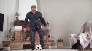 Kapalı alanda futbol topuyla birlikte mutlu, aktif, Kafkas emeklilik eğitimi. Evde futbol oynayıp şutu bırakan sağlıklı yaşlı bir adam. Yaşam tarzı, hobi, spor.