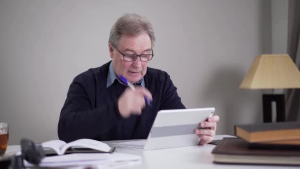 Senior Caucasian businessman scrolling tablet screen and shaking head. Portrait of mature man surfing Internet indoors. Lifestyle, activity, business, overworking. — Stockvideo