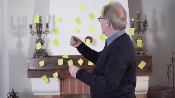 Anciano hombre caucásico pegando notas en la pared y mostrando el pulgar hacia arriba a la cámara. Retrato de jubilado viejo positivo luchando contra la enfermedad de Alzheimers por entrenamiento de memoria. Estilo de vida, envejecimiento, atención médica . — Vídeos de Stock