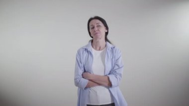 Alaycı bir gülümsemeyle gözlerini kaçıran gururlu beyaz kadın portresi. Beyaz arka planda duran ironik bayan. İroni, iğneleme, küçümseme, yaşam tarzı.