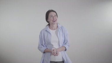 Beyaz arka planda kahkahalarla gülen neşeli beyaz kadın portresi. Neşeli, mutlu esmer kadın içeride konuşuyor ve gülümsüyor. Eğlence, eğlence, yaşam tarzı, mutluluk..