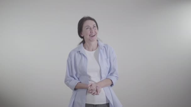 Retrato de la alegre mujer caucásica adulta riendo en voz alta en el fondo blanco. Alegre morena feliz señora hablando y sonriendo en el interior. Alegría, ocio, estilo de vida, felicidad . — Vídeos de Stock