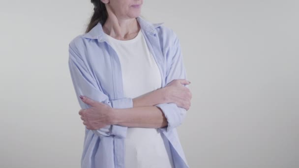 Volwassen onherkenbare blanke vrouw met gekruiste handen op witte achtergrond. Begrip wantrouwen, sarcasme, ironie. — Stockvideo