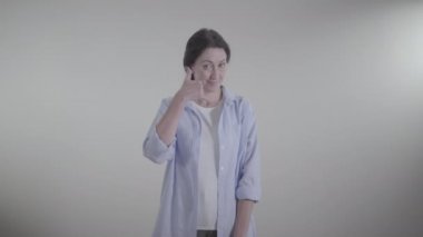 Kendine güvenen bir kadının telefon hareketi yapıp başını sallayarak evet işareti yaptığı bir fotoğraf. Yetişkin, esmer, beyaz bir kadın konuşmak için bekliyor. Yaşam tarzı, iletişim..