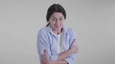 Beyaz arka planda omuzlarını ovuşturan donmuş beyaz kadın. Yetişkin genç bayan soğuk hava gösteriyor. Sezon, yaşam tarzı.