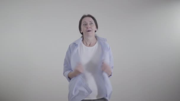 Portret van een blanke vrouw die het warm heeft binnen. Brunette dame schudden kleren en zwaaien handen op het gezicht om af te koelen. Temperatuur, seizoen, levensstijl. — Stockvideo