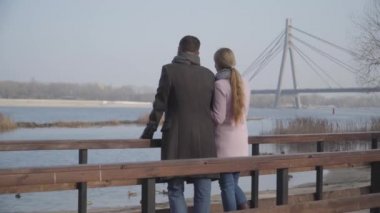 Yetişkin beyaz bir çiftin şehir parkında köprüde dikilip sohbet edişinin arkası. Nehre bakan ve dışarıda sohbet eden zarif bir kadın ve erkek. Çıkma, aşk, romantizm, yaşam tarzı.