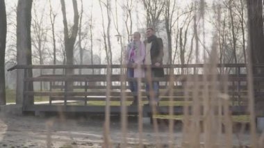 Mutluluktan gülümseyen adam ve kadının kuşlar gibi sohbet edişinin geniş bir görüntüsü. Sonbahar parkında yaş farkı olan romantik beyaz bir çift. Aşk, evlilik, ilişki, aşk.