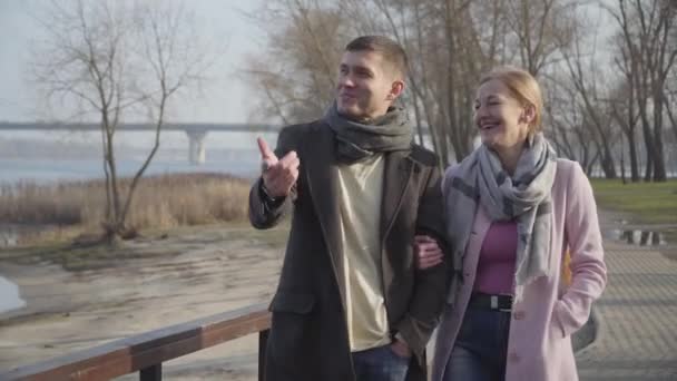 Portrait d'un heureux couple caucasien adulte se promenant le long de l'allée du parc et parlant. Souriant homme plus jeune et femme plus âgée bavarder. Mari et femme se reposant à l'extérieur . — Video