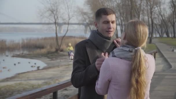 Feliz esposo más joven y esposa mayor arreglando las bufandas del otro y dejando juntos en el parque. Pareja sonriente enamorada paseando al aire libre. Ocio, amor, romance . — Vídeos de Stock