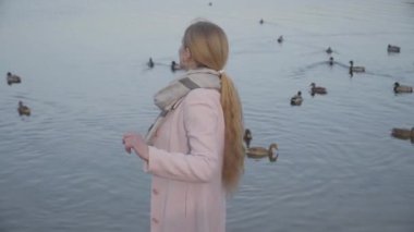 Mutlu sarışın beyaz kadın kameraya dönüyor ve sonbahar nehrinin arka planında gülümsüyor. Hafta sonlarını nehir kıyısında geçiren neşeli yetişkin kadın portresi. Yalnızlık, yaşam tarzı, neşe.