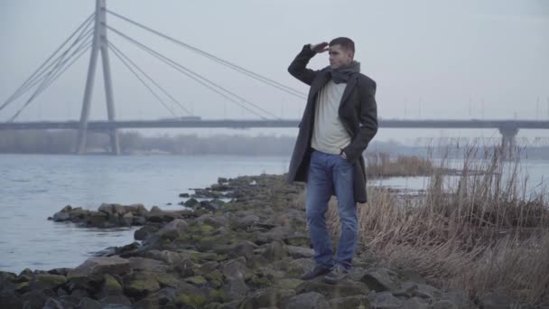 Portret van een zelfverzekerde jonge blanke man die hand in hand naar het voorhoofd kijkt en wegkijkt. Elegante brunette die rust uit de stad in het park op herfstdag. Vreugde, levensstijl, natuur, ontspanning. — Stockvideo