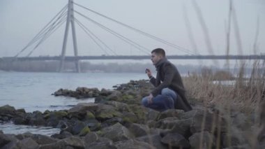Nehir kıyısında oturan ve suya taş atan düşünceli Kafkas delikanlısı. Bunalımda olan üzgün yakışıklı adamın portresi yalnız bir sonbahar gününü dışarıda geçiriyor. Yaşam tarzı, yalnızlık, doğa..