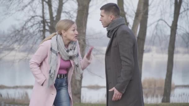 Een blanke man die een volwassen vrouw bedreigt. Een gestresste vrouw die zijn arm stopte en een boze man alleen liet in het park. Conflict, vernedering, geweld. — Stockvideo