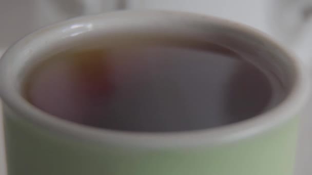 Primo piano estremo di zucchero che cade in tazza di tè nero. Persona sconosciuta che aggiunge glucosio organico cristallino alla bevanda. Mattina, stile di vita, bevanda aromatica . — Video Stock